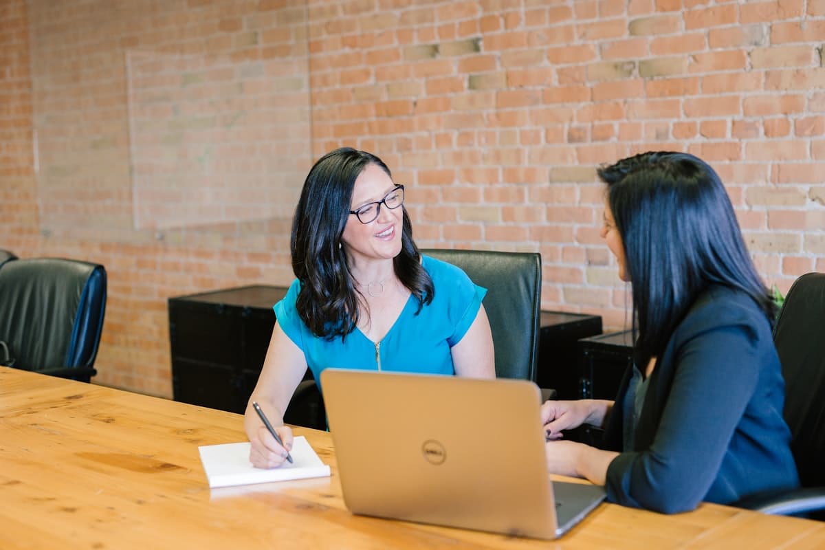 Two colleagues pairing on a laptop with handwritten notes