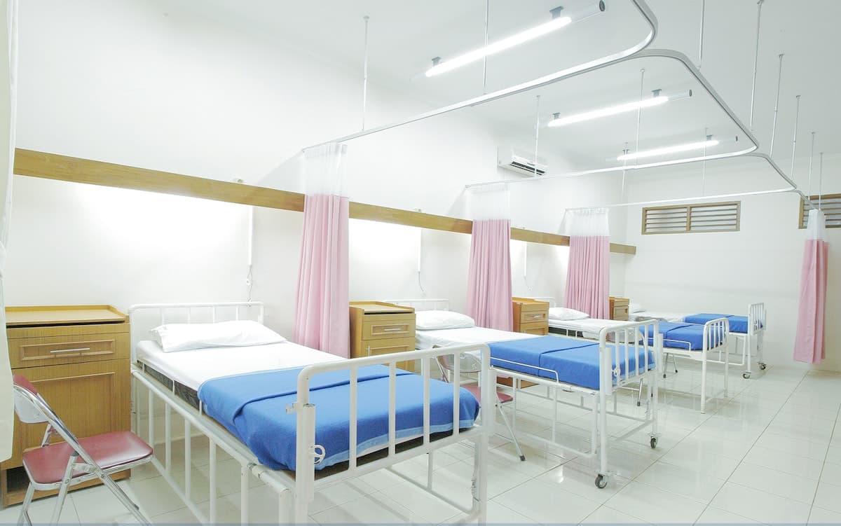A bright empty hospital ward with privacy curtains