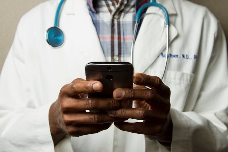 A clinician using a smartphone with a stethoscope around the neck