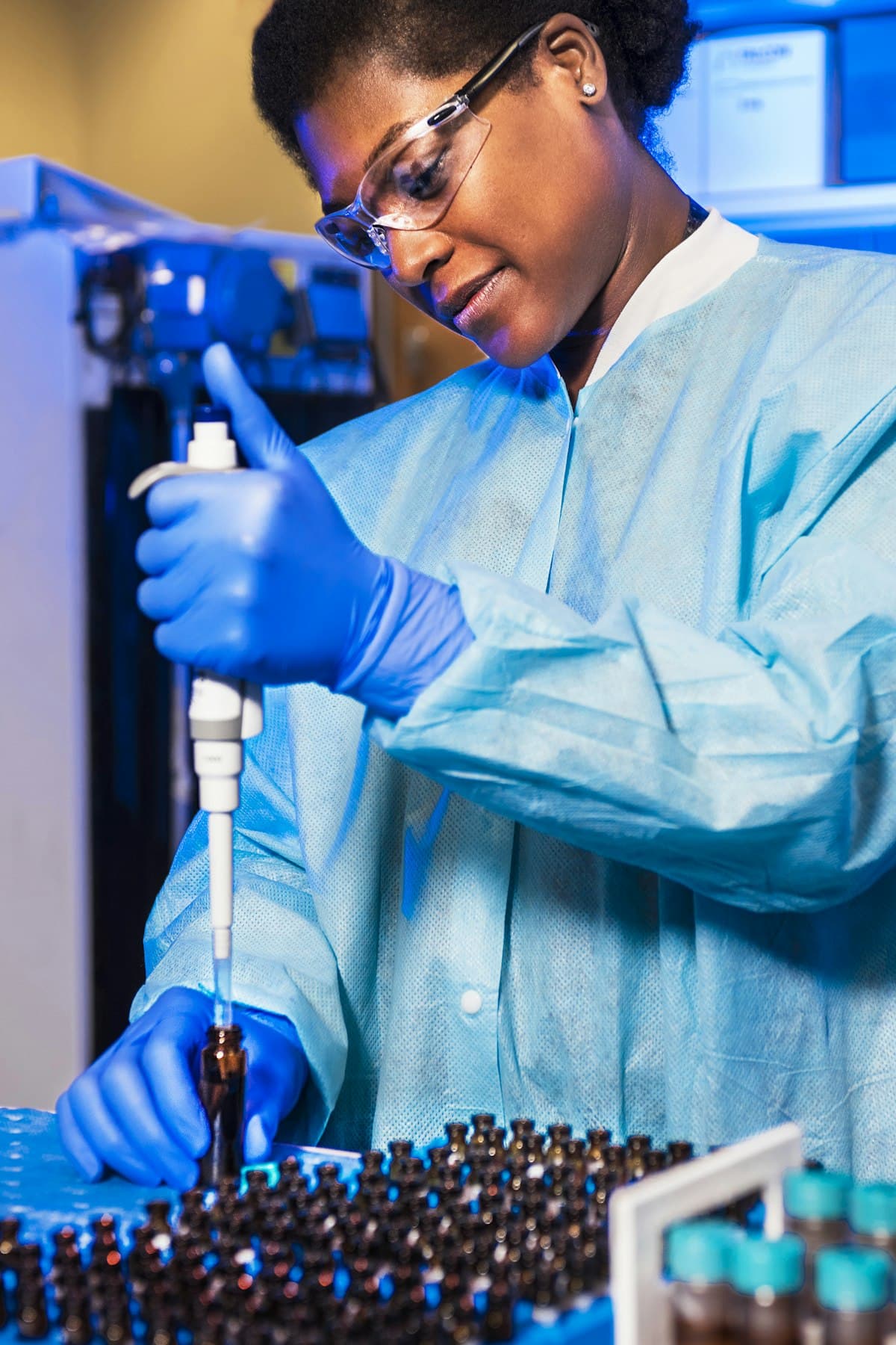 A laboratory technician with a pipette and reagent vials